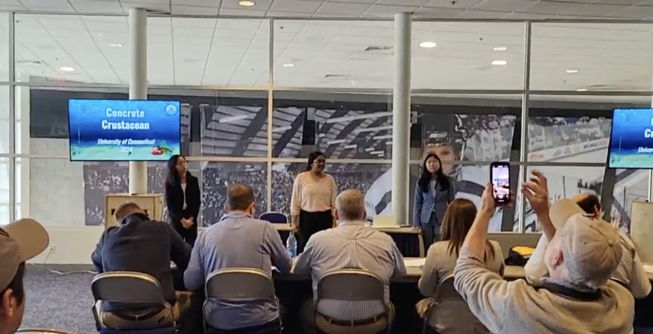 3 members presenting the concrete crustacean at the competition in front of a panel of judges 